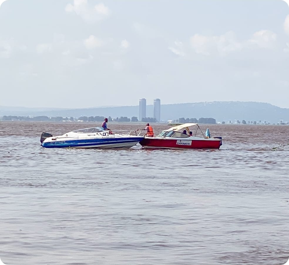 Guests on a boat outing on the Congo River with the Kinshasa shoreline in view.