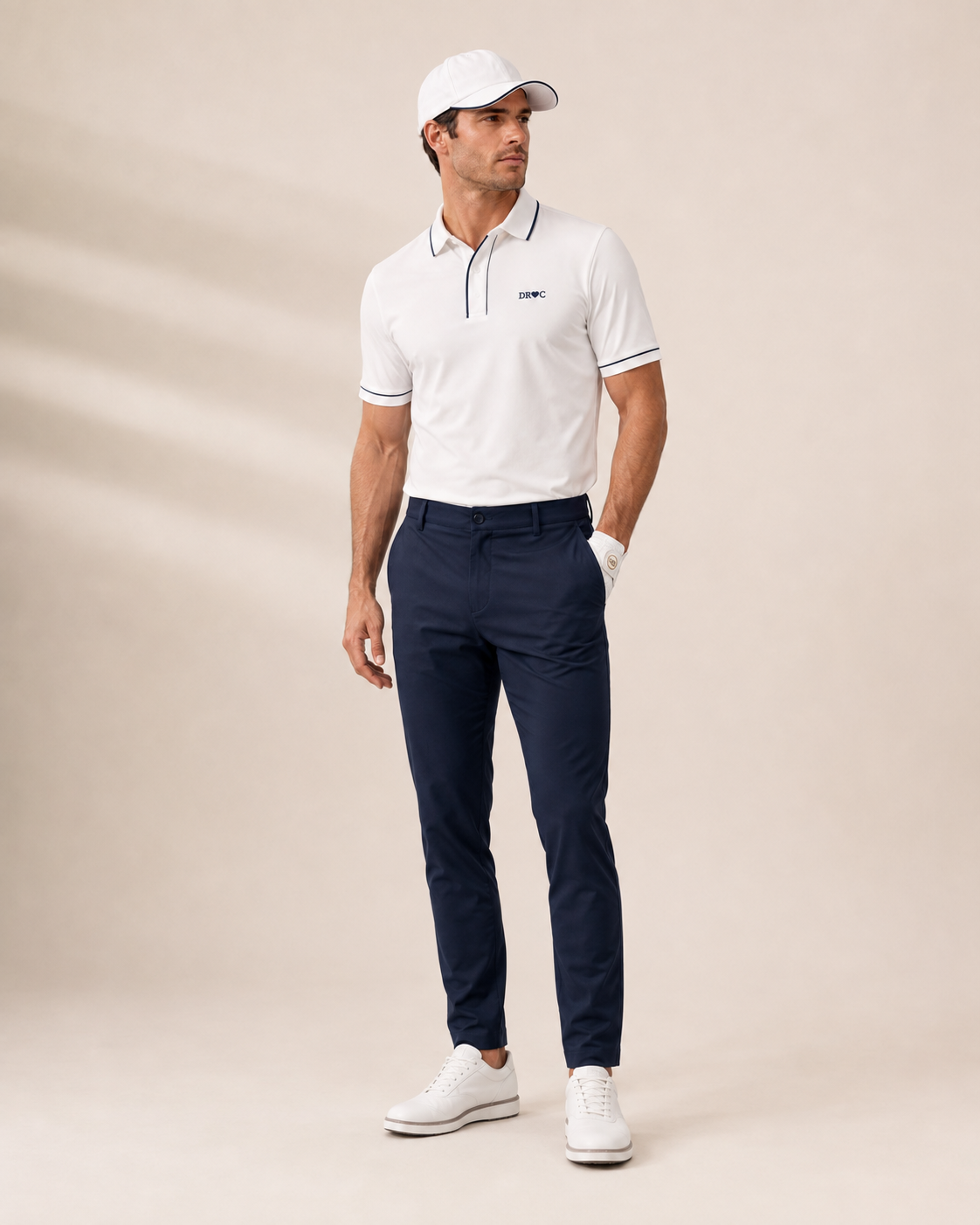 Man wearing the DRCTOURISM cream golf polo with navy tipping and navy tailored golf trousers