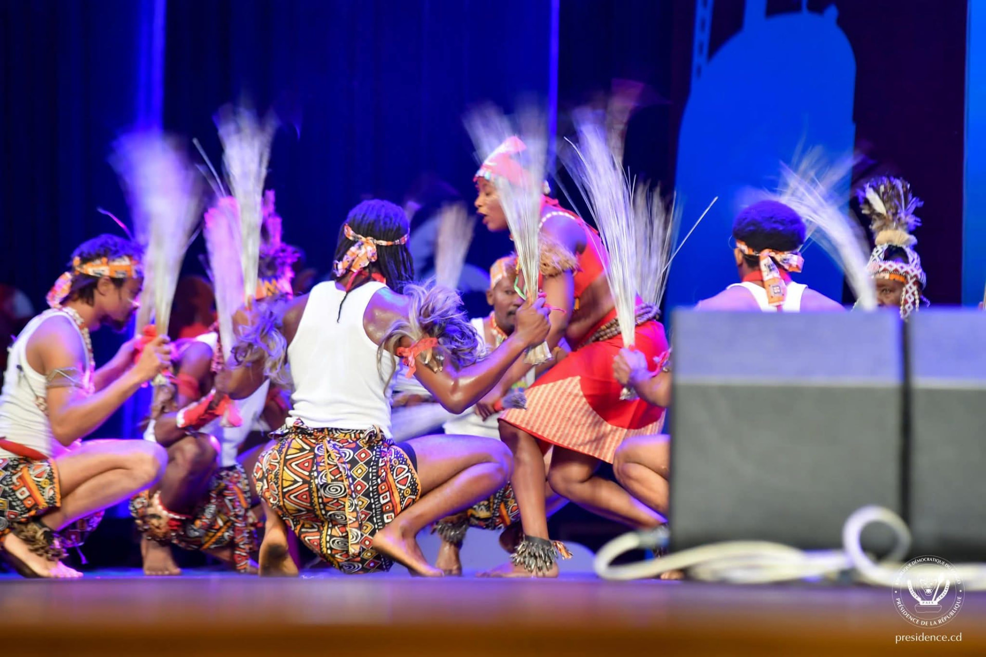 A Congolese folkloric troupe performing on stage in traditional dress.