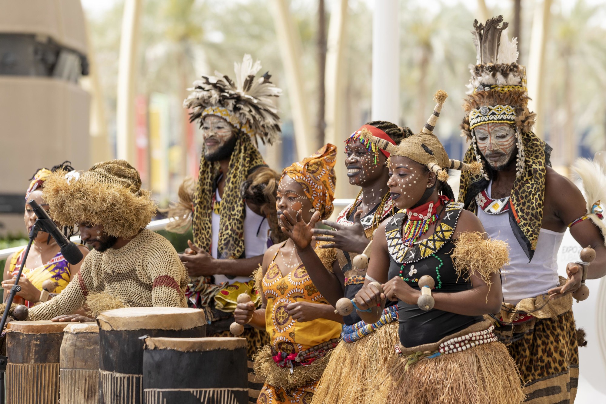 Congolese musicians and dancers in traditional dress performing with drums and percussion at a cultural celebration.