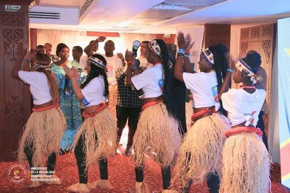 Congolese dancers in raffia costume performing for families at a cultural evening.