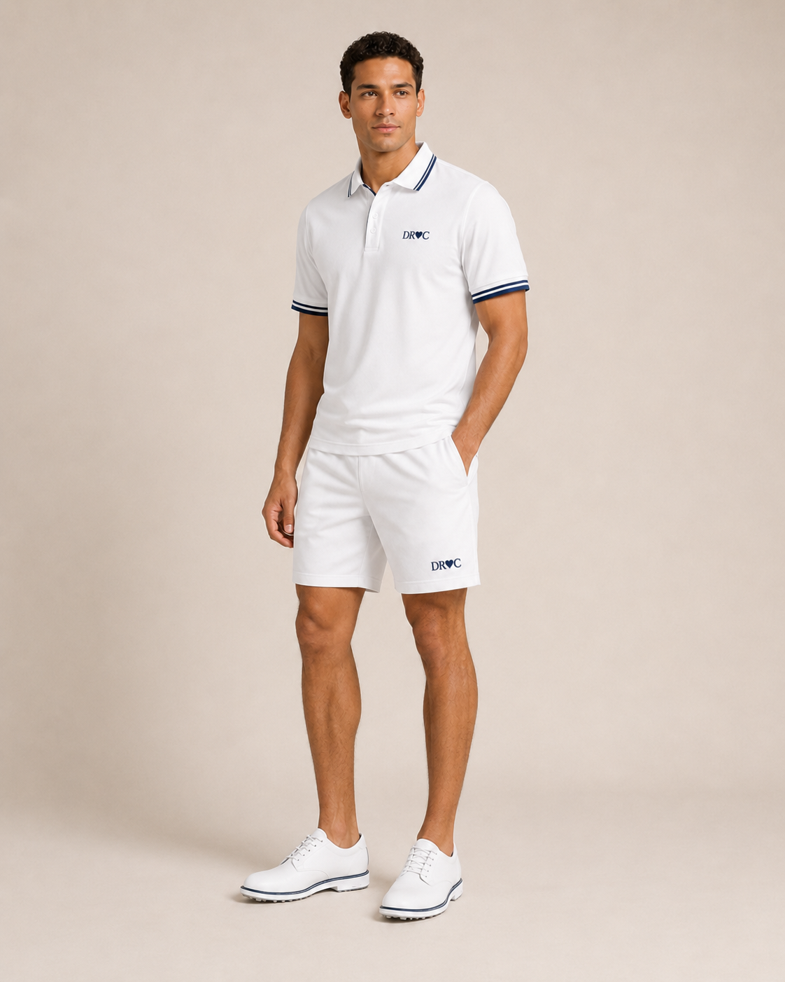 Man wearing the DR♥C white golf polo with navy tipped collar and cuffs, with matching white golf shorts