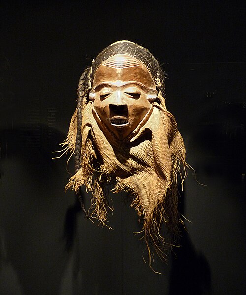 Carved Pende mask with raffia beard displayed in a museum collection