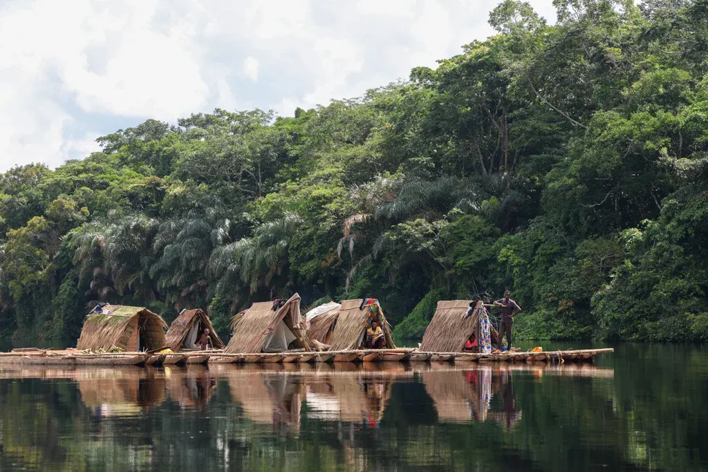 Floating thatched-roof river camps reflected on the Congo River at the rainforest edge — 6-day Congo River expedition